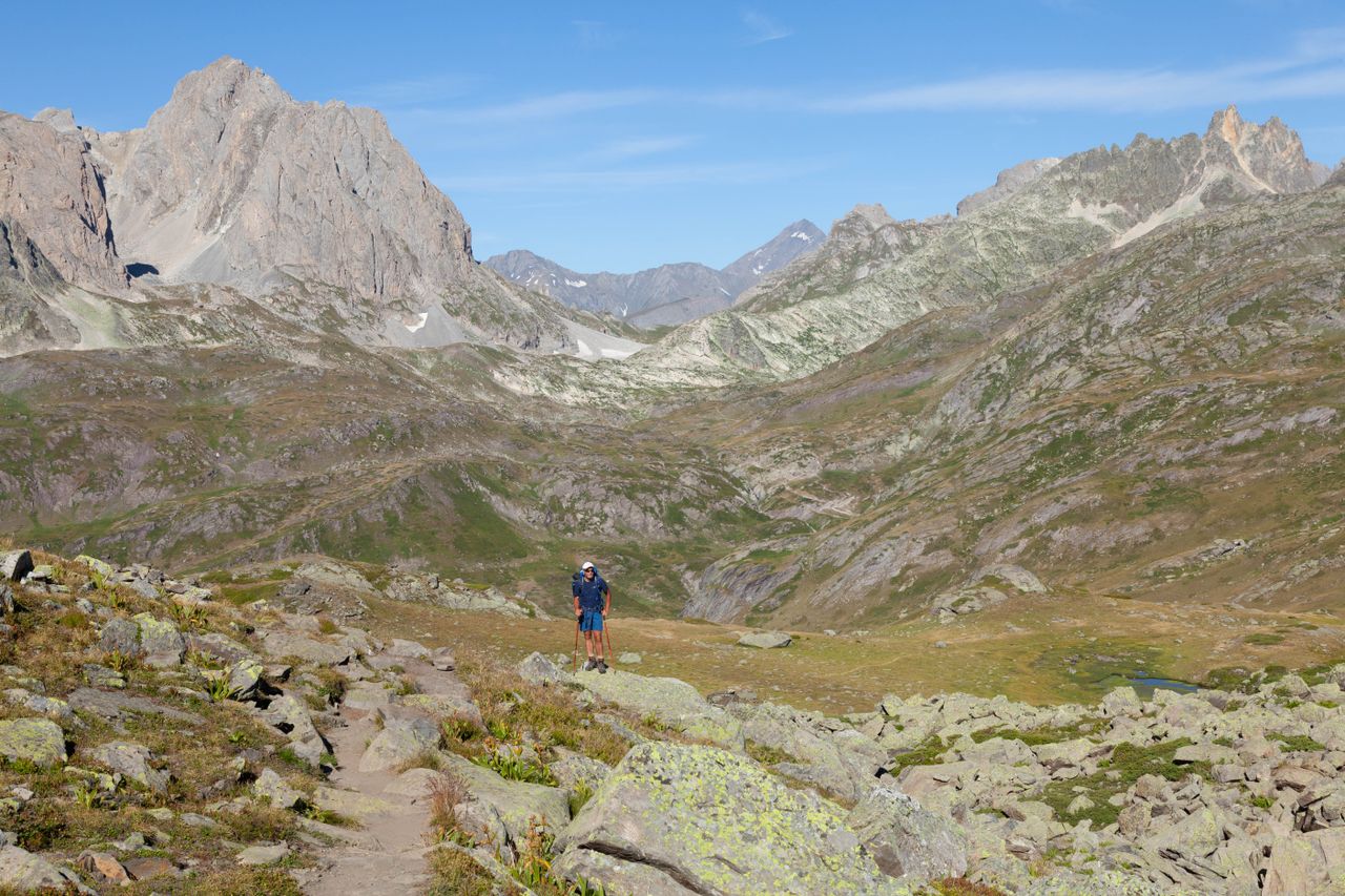 Lone hiker explores stunning rocky landscapes in Névache, France.